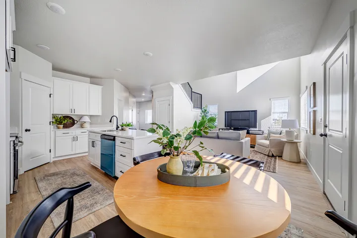 Open-concept living space featuring wood-finish flooring, white cabinetry, a kitchen island with seating, a stainless steel dishwasher, and recessed lighting