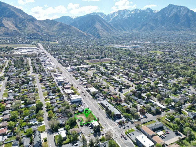 Aerial perspective showcasing a parcel of land marked in green, surrounded by residential and commercial structures