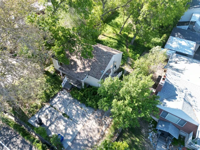 Single-story residence with a pitched shingle roof, surrounded by mature trees
