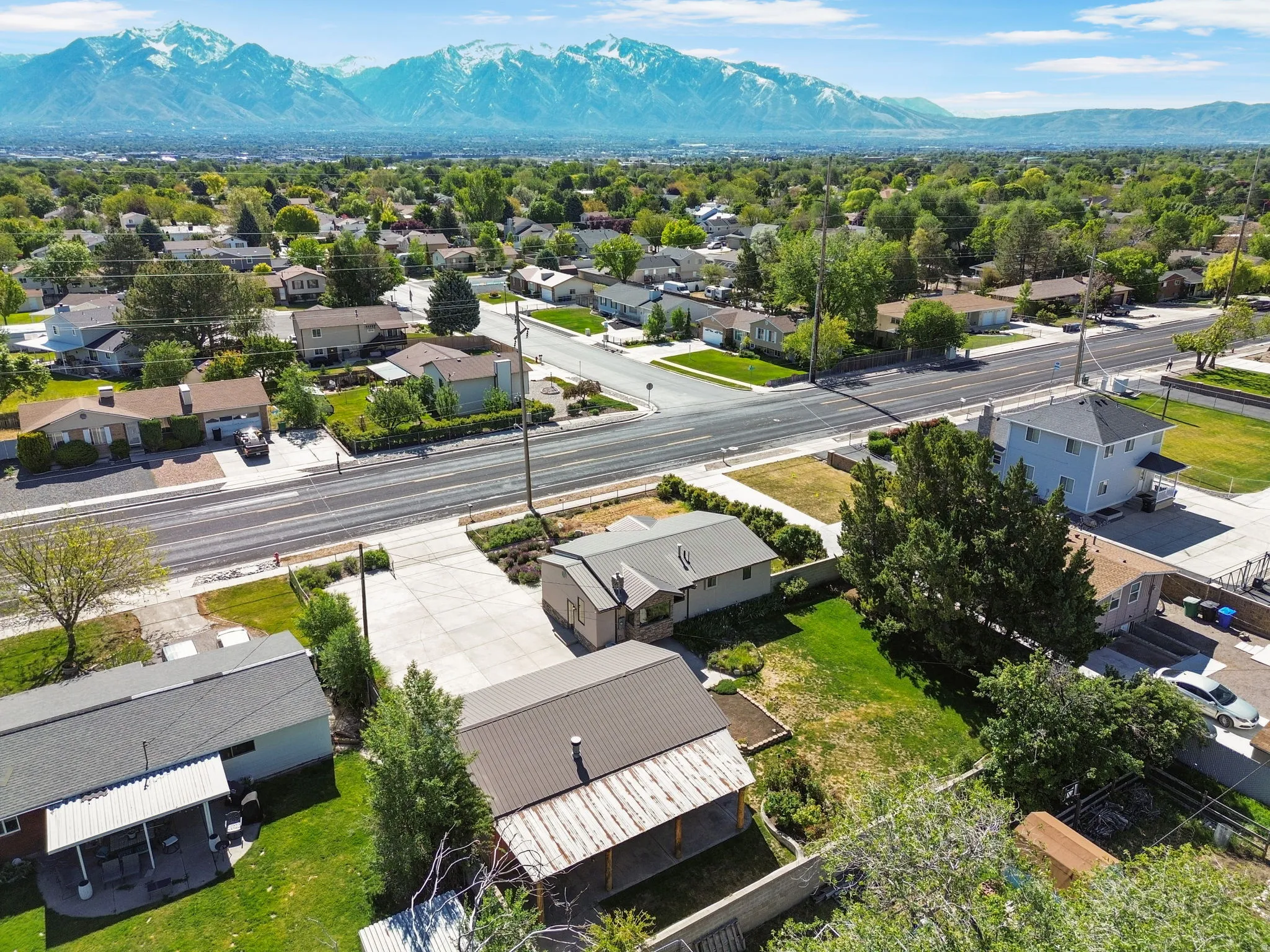 Residential neighborhood with diverse home styles and street access, featuring a prominent mountainous backdrop. Aerial View #3.