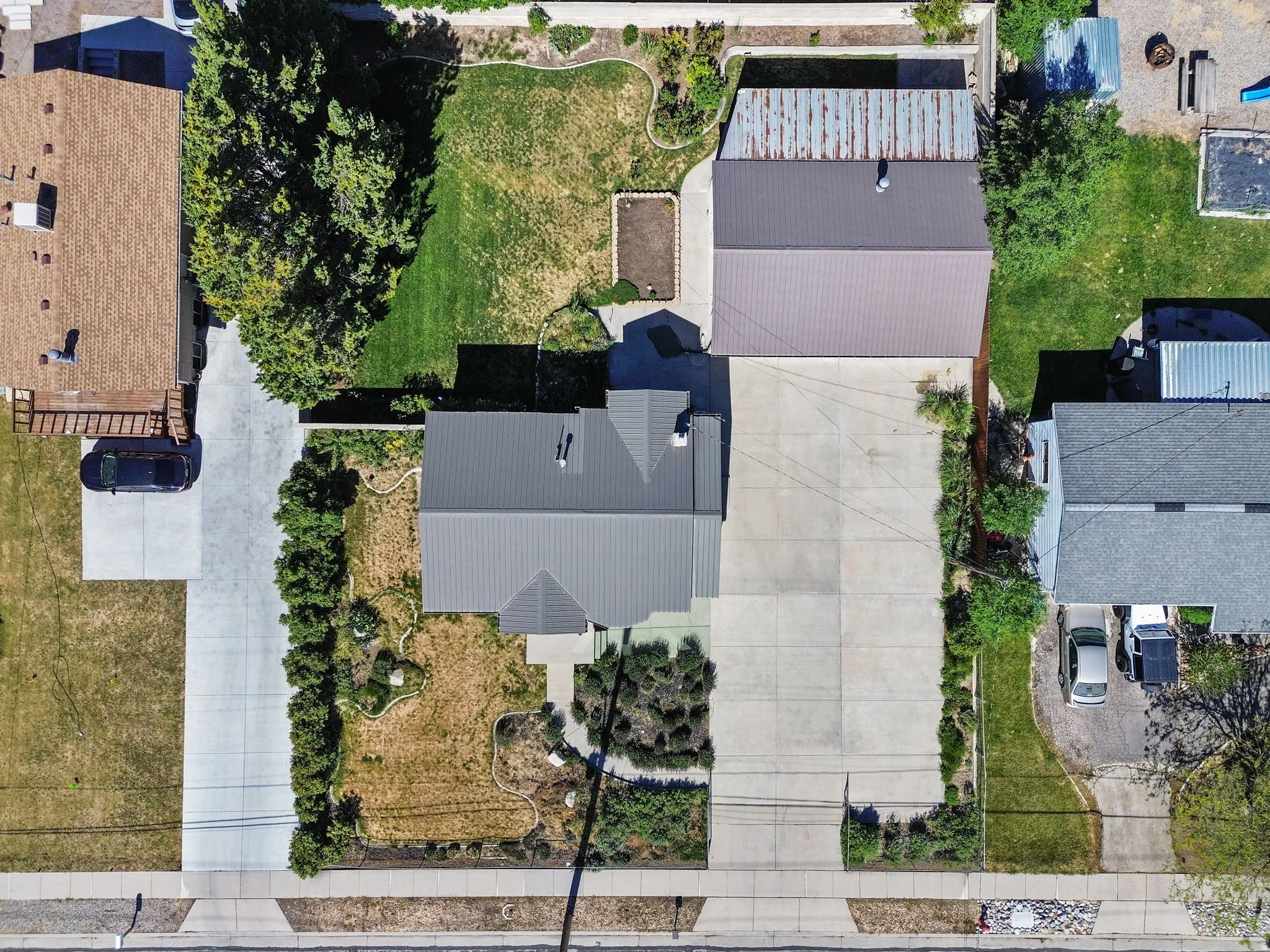 Expansive concrete driveway leading to a detached garage with a metal roof. Aerial View #1.