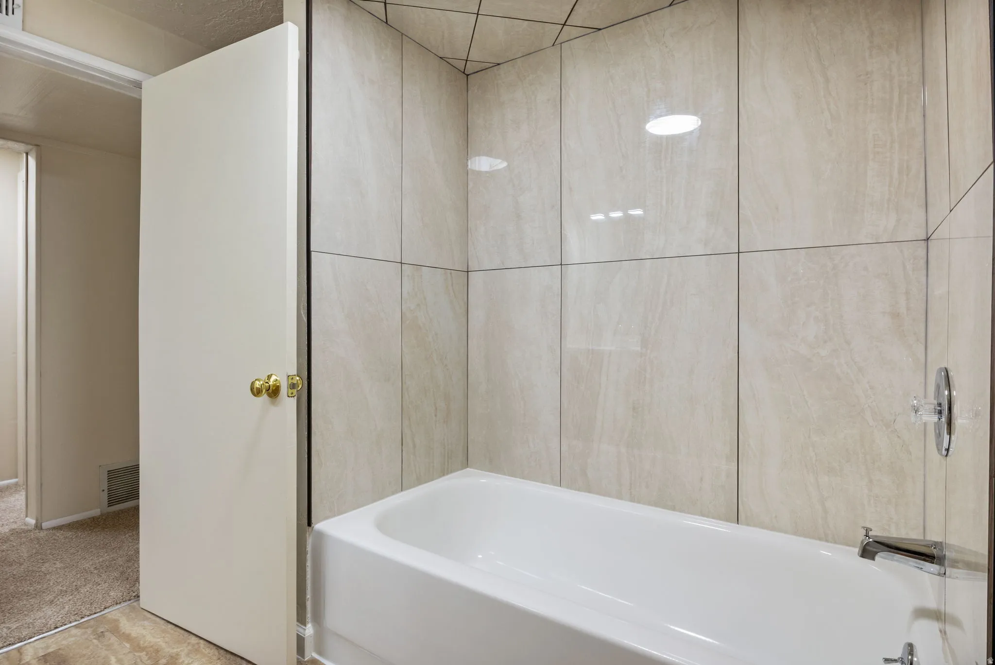 Bathtub with chrome fixtures and light-toned, large format tile surround. Basement Bathroom-View #1.