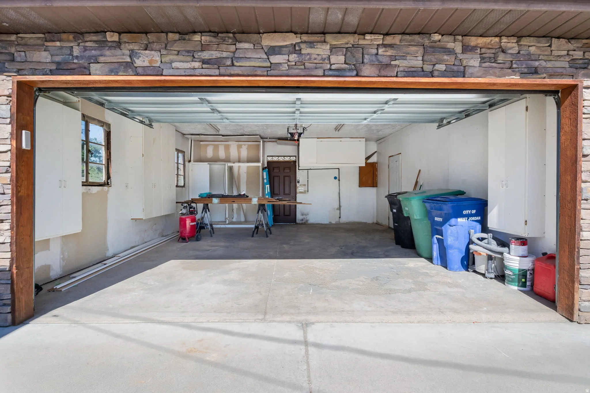 Expansive two-car garage with a concrete floor, built-in cabinetry, and two windows providing natural light.