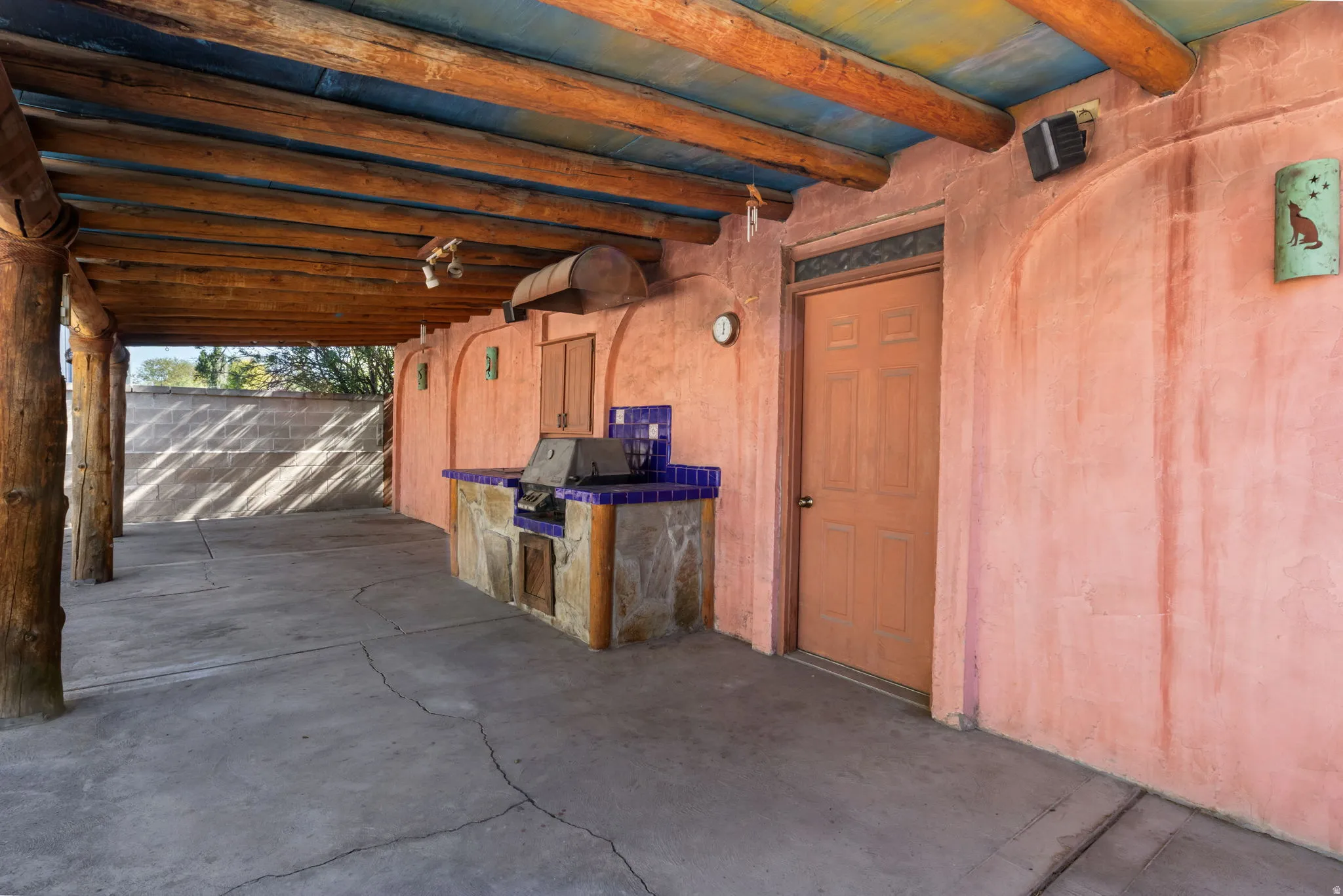 Covered patio featuring exposed wood beams and a concrete floor. Built in gas grill.