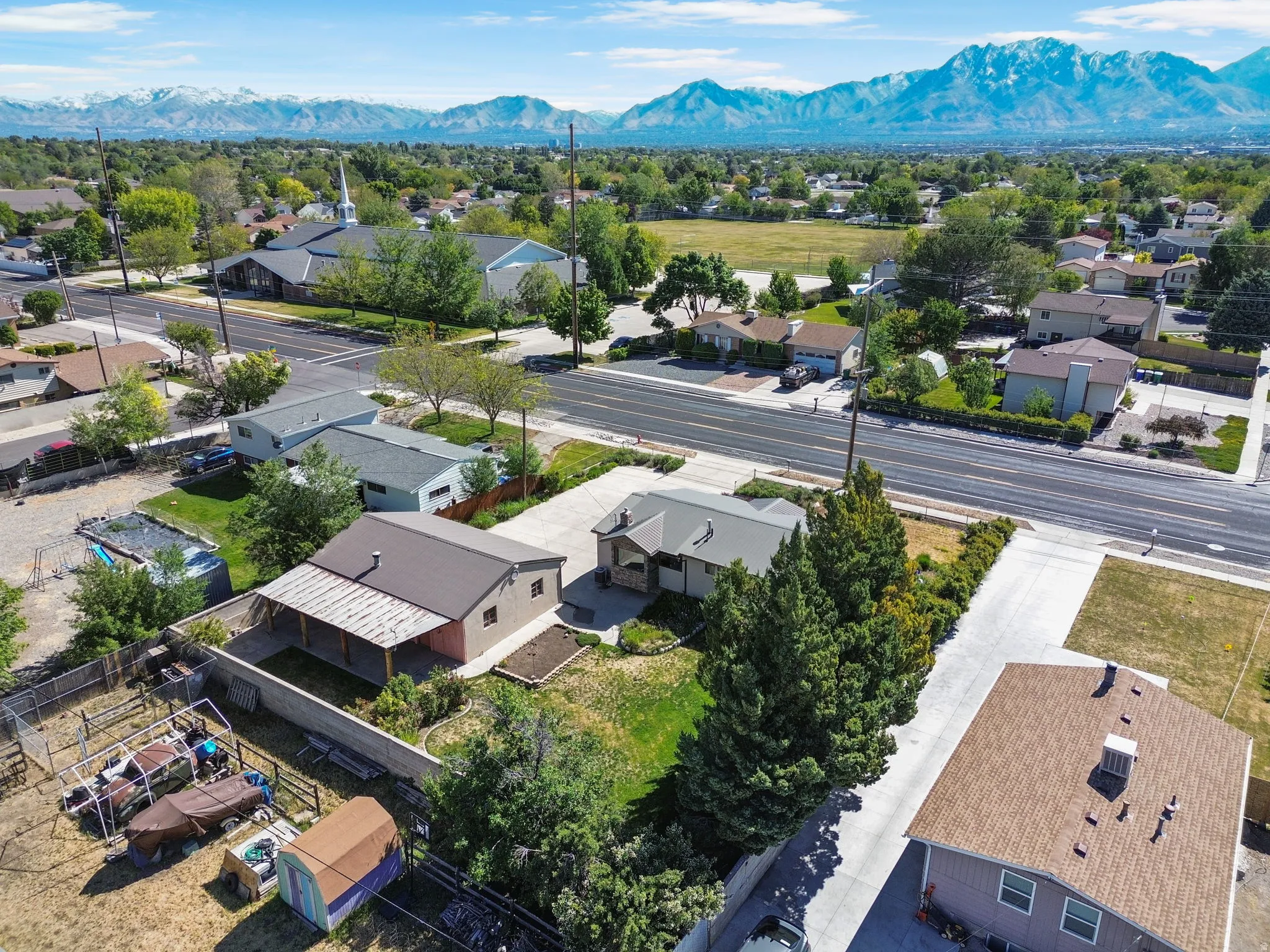 Property featuring a brown metal roof, covered patio, and concrete block retaining wall. Aerial View #4.