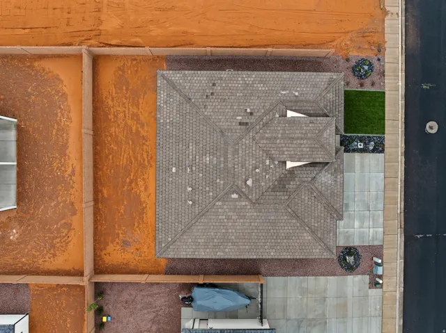 Aerial perspective showcasing the property's shingle roofline, concrete driveway, and a fenced perimeter