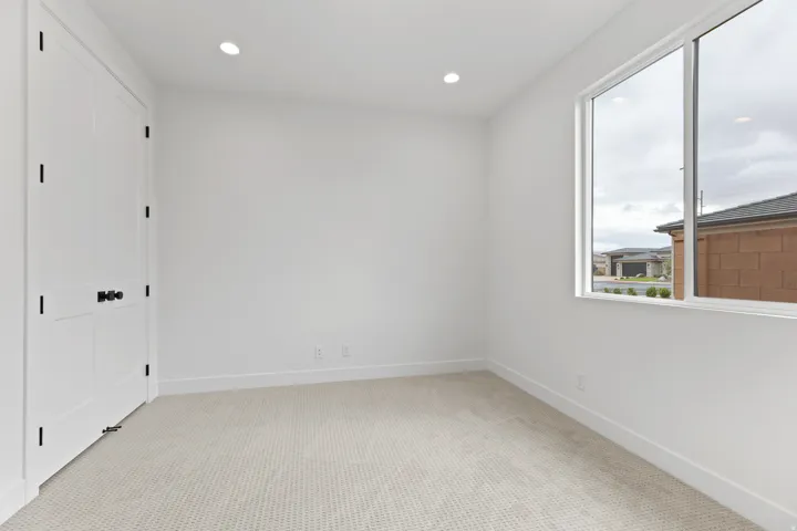 Bright room featuring a large window, recessed lighting, white walls, and light-toned carpet flooring