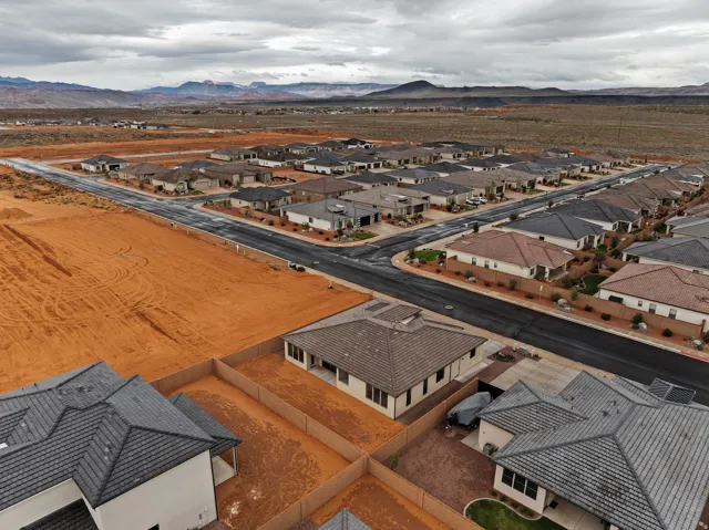 Residential community featuring single-story homes with tile roofs, paved streets, and desert landscaping