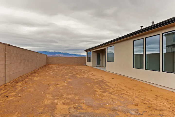 Spacious backyard area featuring a perimeter concrete block wall, an exterior patio, and large windows