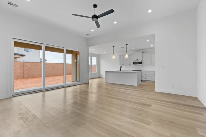 Open-concept living area featuring light wood-finish flooring and a contemporary ceiling fan