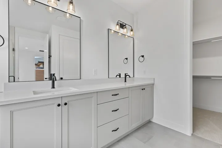 Dual vanity with white cabinetry and quartz countertops, featuring integrated sinks and matte black fixtures