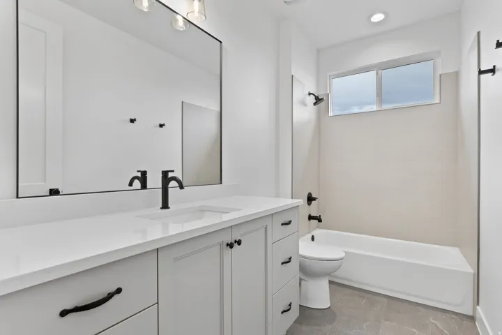 Bathroom featuring a white vanity with a quartz countertop, an undermount sink, and black fixtures