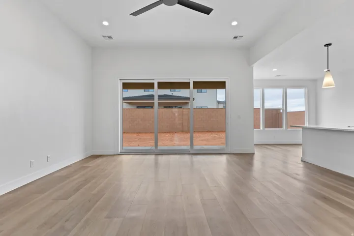 Expansive living area with wood-finish flooring, recessed lighting, and a contemporary ceiling fan