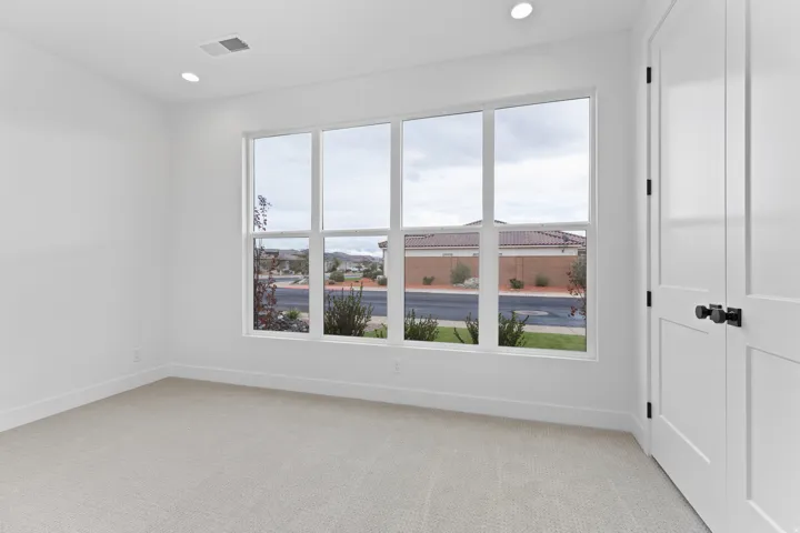 Bright room featuring a large multi-pane window, recessed lighting, and light-toned carpeting
