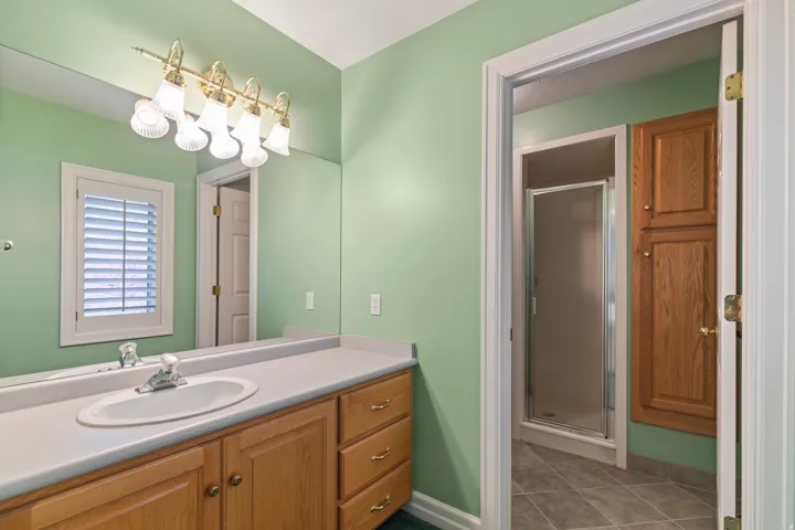 Full bathroom featuring a shower stall, vanity, and dark tile patterned floors