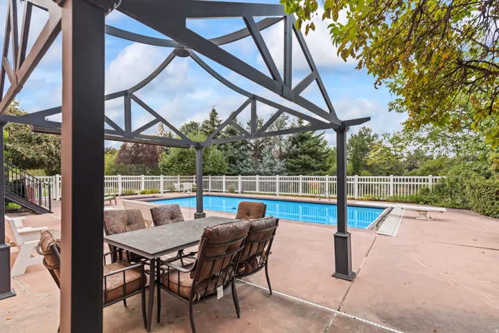 View of swimming pool featuring patio surround, a fenced backyard, a diving board, and outdoor dining space