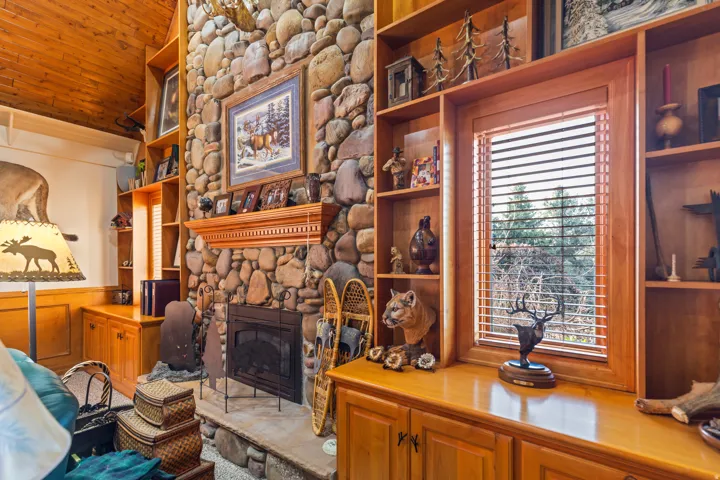 Living room with built in shelves, a fireplace, and wooden ceiling