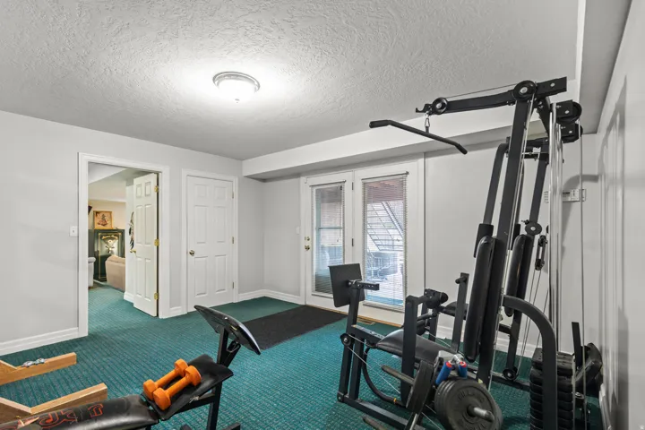 Workout room featuring a textured ceiling and dark colored carpet