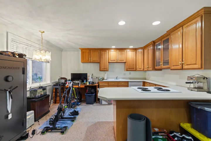 Kitchen featuring wood finish cabinetry, light countertops, a peninsula, a desk, and glass fronted cabinets