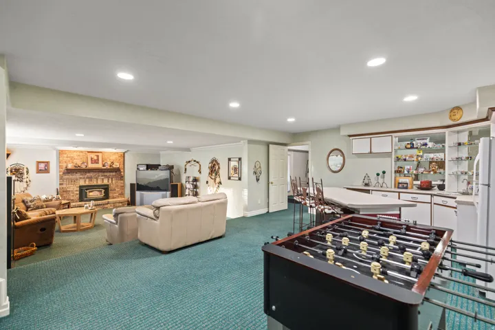 Rec room with dark carpet, a brick fireplace, recessed lighting, and a dry bar