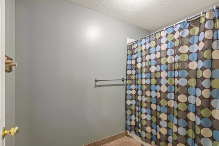 Full bathroom with curtained shower, a textured ceiling, and light tile patterned floors