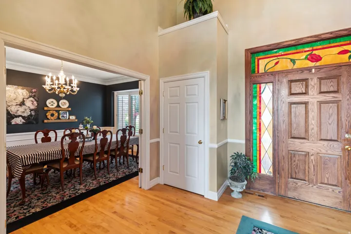 Foyer entrance with a chandelier, light wood finished floors, a high ceiling, and crown molding