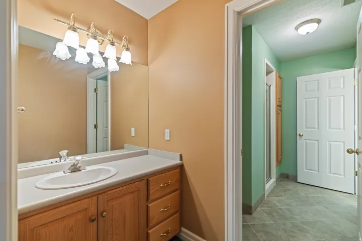Full bathroom with vanity, a stall shower, light tile patterned floors, and a textured ceiling