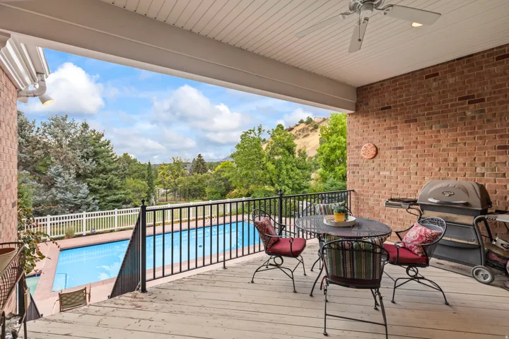 Wooden deck with ceiling fan, outdoor dining space, and view of scattered trees