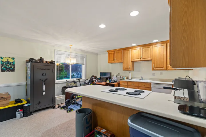Kitchen featuring light countertops, a peninsula, white appliances, a chandelier, and light colored carpet