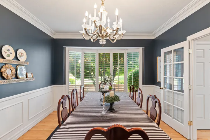 Dining space with plenty of natural light, ornamental molding, light wood-type flooring, wainscoting, and hanging lights