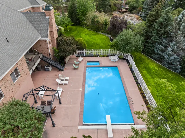 View of swimming pool with patio surround, a fenced backyard, and a diving board
