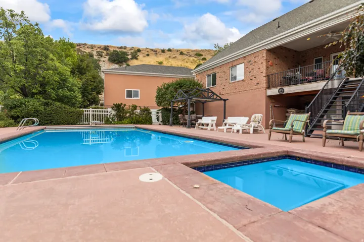 View of swimming pool featuring patio surround and a balcony