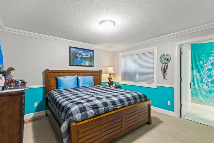 Bedroom featuring a textured ceiling, crown molding, and carpet