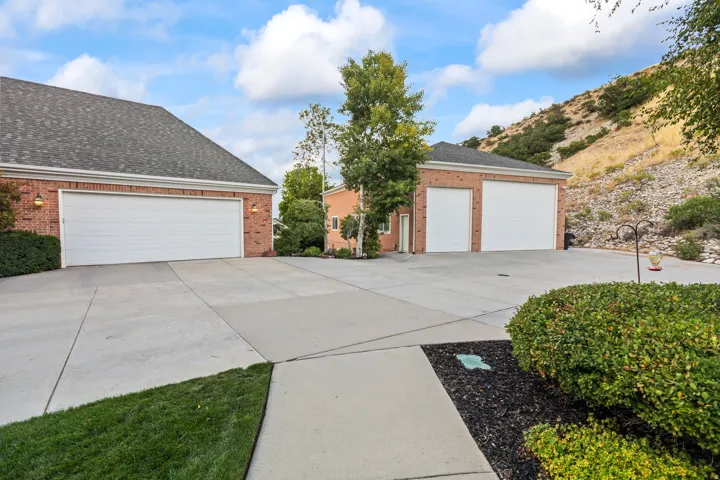 View of front of house featuring brick siding, a garage, a shingled roof, and an outdoor structure