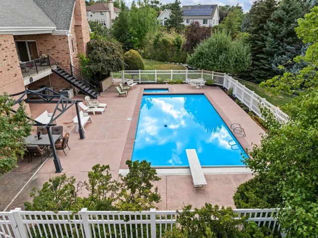 View of pool featuring a fenced backyard, patio surround, a diving board, and view of wooded area