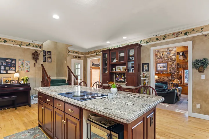 Kitchen featuring light wood-style flooring, light stone countertops, crown molding, beverage cooler, and a kitchen island