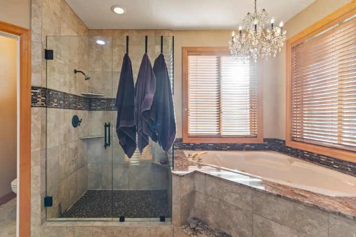Full bathroom with a stall shower, a jetted tub, and a chandelier
