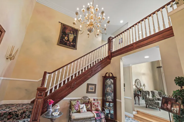 Stairs with ornamental molding, a chandelier, and a high ceiling