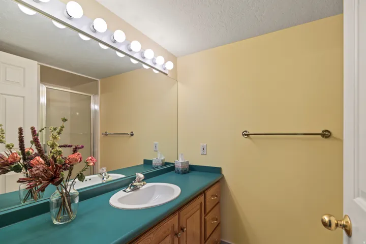 Full bath featuring vanity, a stall shower, and a textured ceiling
