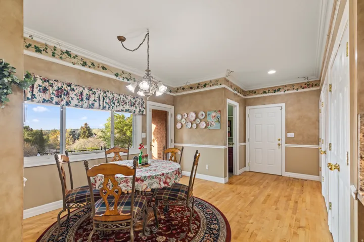 Dining space with light wood-type flooring, a chandelier, and ornamental molding