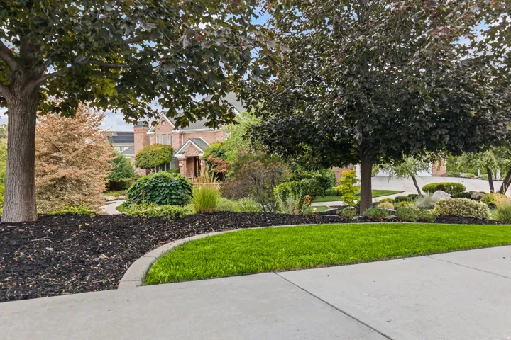 View of property hidden behind natural elements featuring a front yard and brick siding