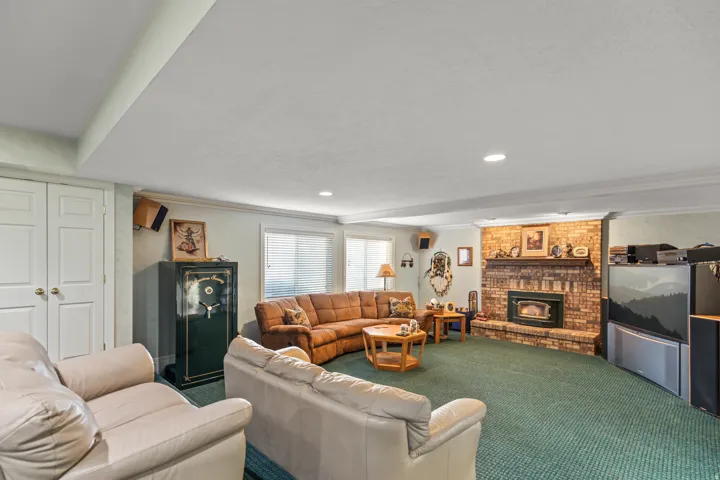 Living room featuring a brick fireplace, crown molding, and carpet floors