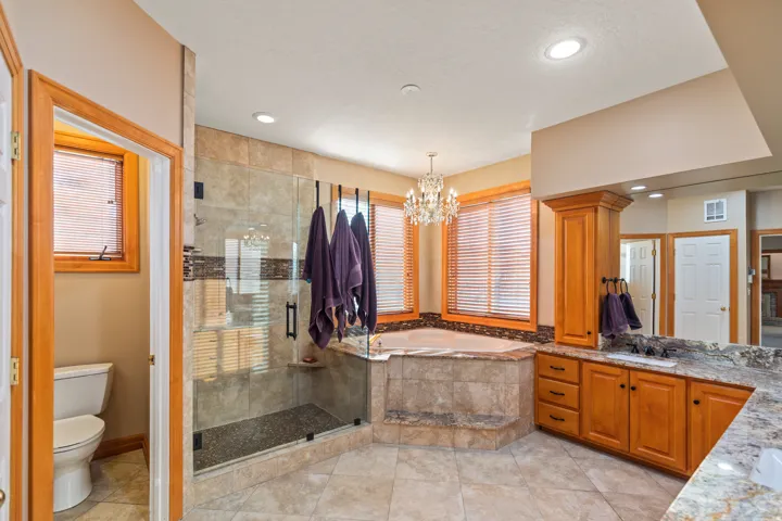 Bathroom with vanity, a stall shower, a garden tub, a chandelier, and light tile patterned floors