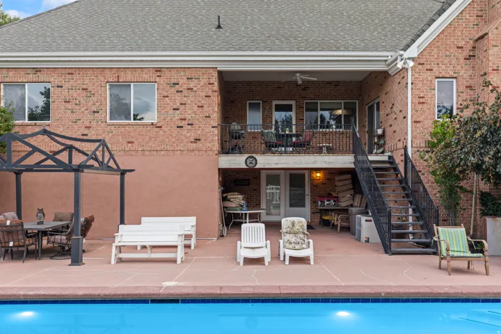 Rear view of property with outdoor dining area, a patio area, brick siding, an outdoor pool, and roof with shingles