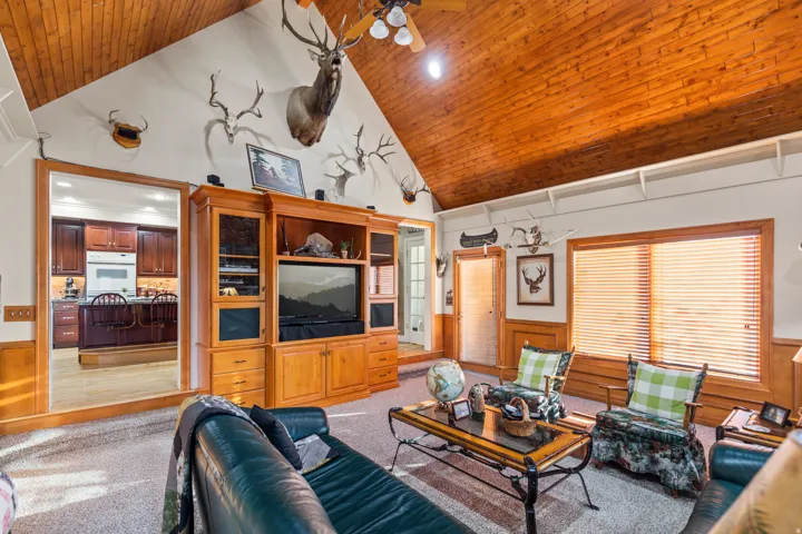 Living room with wainscoting, a vaulted wooden ceiling, wooden walls, recessed lighting, and light colored carpet
