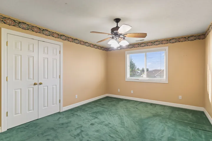 Unfurnished bedroom with carpet, a closet, and a ceiling fan
