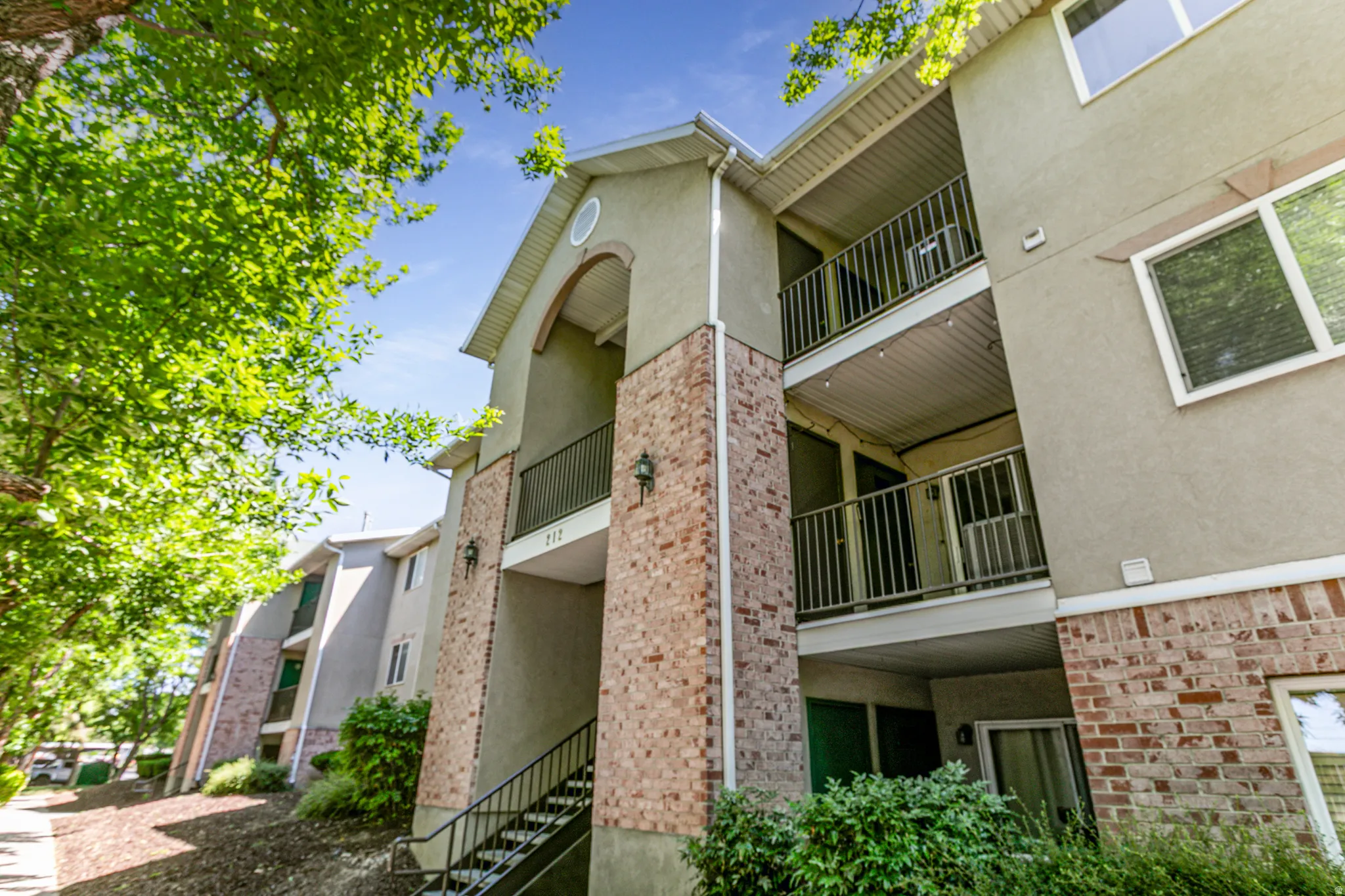 Multi-level building exterior featuring stucco siding and brick accents
