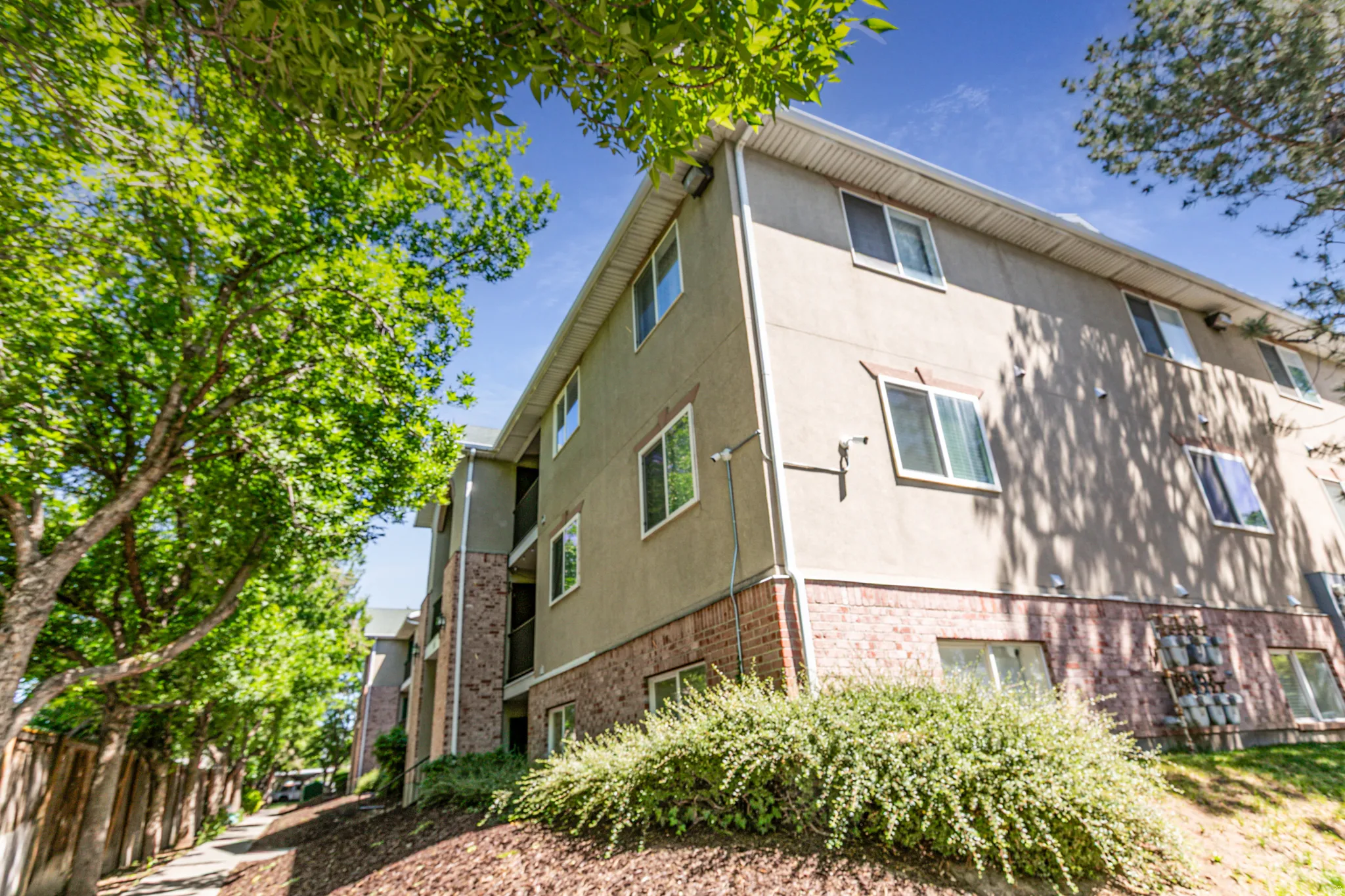 Multi-level building exterior featuring stucco siding and a brick base