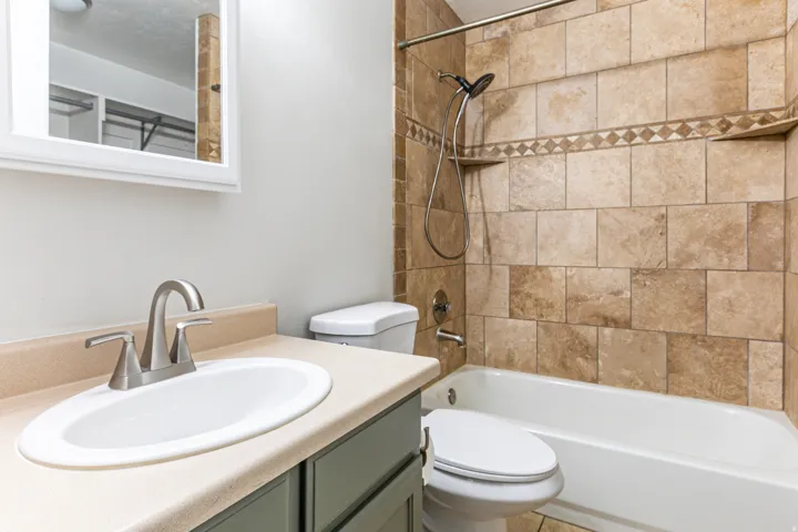 Bathroom featuring a neutral-toned vanity with an integrated sink and brushed nickel faucet