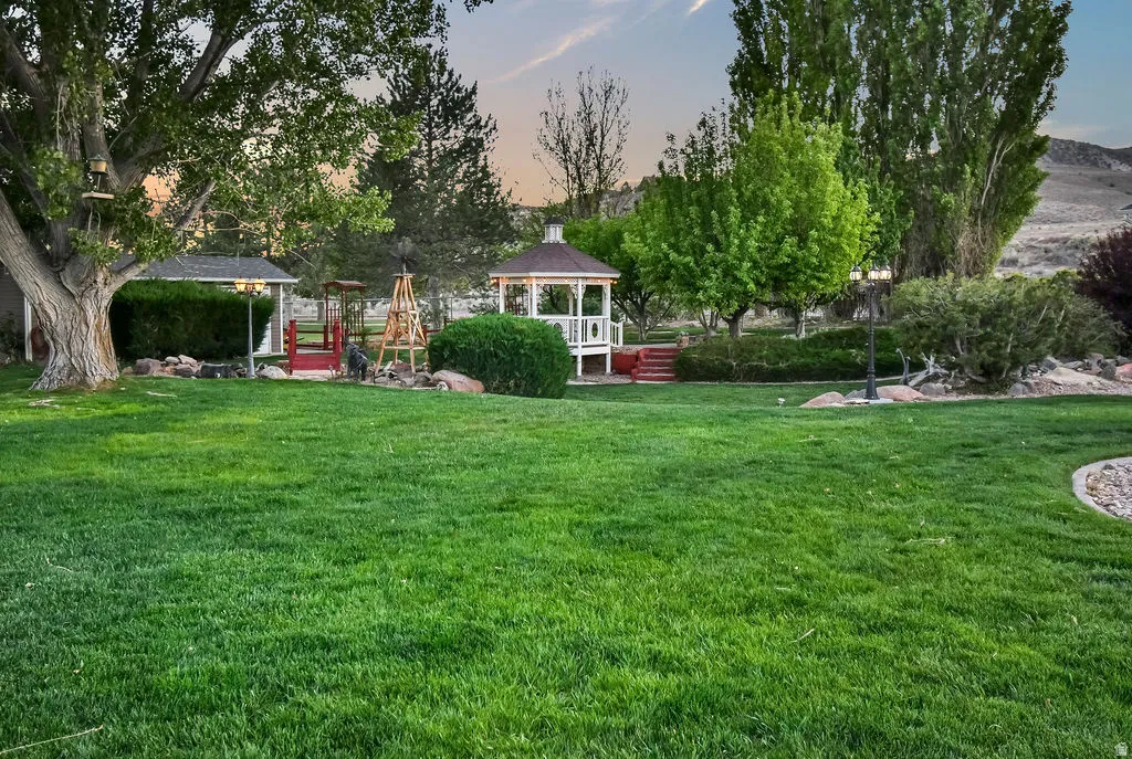 Expansive green lawn with mature trees and a white gazebo